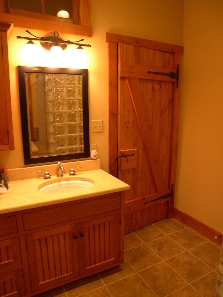 This is an example of a large arts and crafts master bathroom in Philadelphia with shaker cabinets, medium wood cabinets, beige walls, ceramic floors, an undermount sink, solid surface benchtops, an alcove tub, an open shower, beige floor and an open shower.