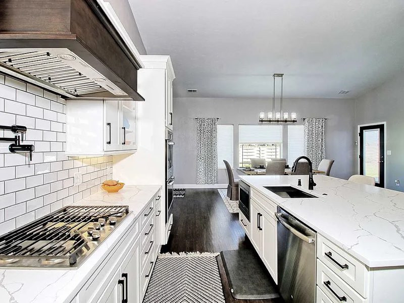 Exempel på ett mellanstort lantligt vit vitt kök, med en undermonterad diskho, skåp i shakerstil, vita skåp, bänkskiva i kvarts, vitt stänkskydd, stänkskydd i tunnelbanekakel, rostfria vitvaror, mörkt trägolv, en köksö och brunt golv