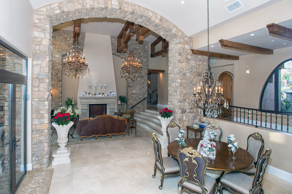 Photo of a large mediterranean open plan dining in San Diego with beige walls, marble floors, a standard fireplace and a stone fireplace surround.