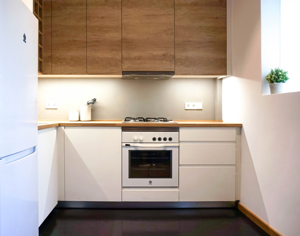 Design ideas for a small scandinavian l-shaped open plan kitchen in Barcelona with a single-bowl sink, flat-panel cabinets, medium wood cabinets, wood benchtops, grey splashback, cement tile splashback, white appliances, concrete floors, no island, black floor and beige benchtop.
