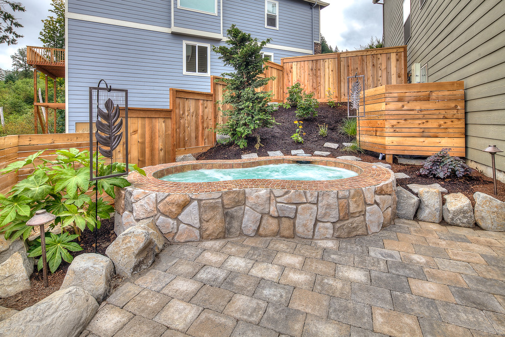 This is an example of a large traditional backyard kidney-shaped pool in Portland with a hot tub and concrete pavers.