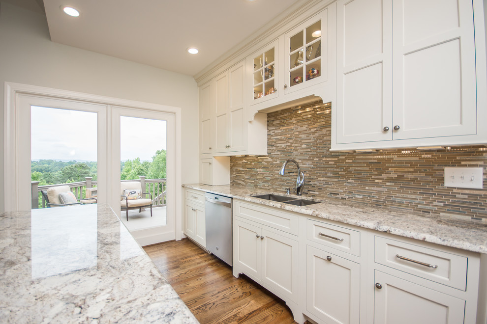 Huge transitional l-shaped medium tone wood floor eat-in kitchen photo in Birmingham with an undermount sink, recessed-panel cabinets, white cabinets, granite countertops, multicolored backsplash, glass tile backsplash, stainless steel appliances and an island