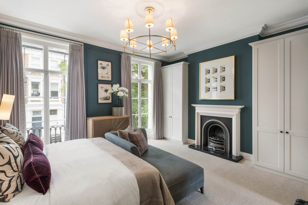 Mid-sized transitional master bedroom in London with blue walls, carpet, a standard fireplace, a stone fireplace surround, beige floor and panelled walls.