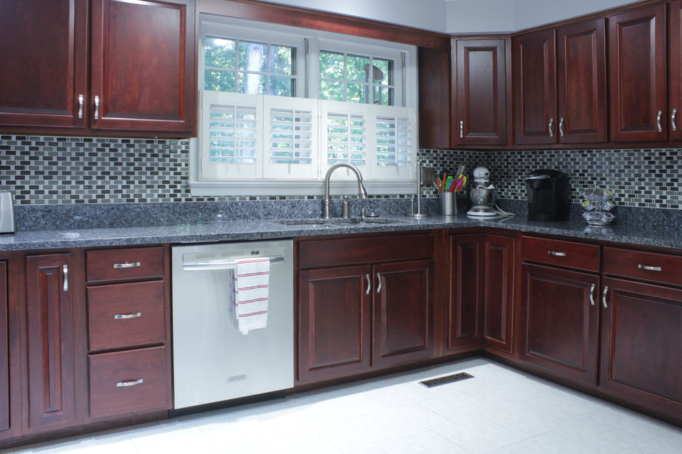 Photo of a mid-sized traditional l-shaped eat-in kitchen in DC Metro with an undermount sink, raised-panel cabinets, dark wood cabinets, granite benchtops, grey splashback, glass tile splashback, stainless steel appliances, ceramic floors and a peninsula.