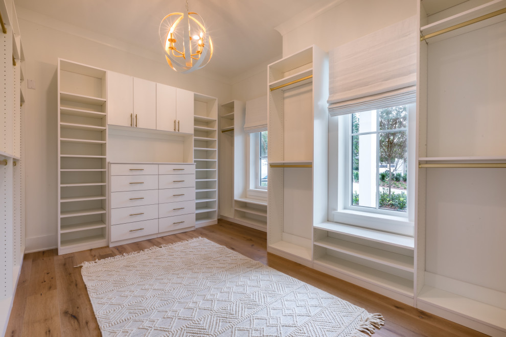 Design ideas for a mid-sized country women's walk-in wardrobe in Orlando with shaker cabinets, white cabinets, medium hardwood floors and brown floor.