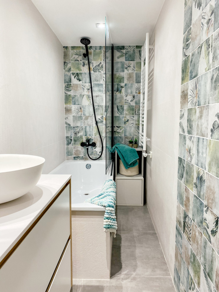 This is an example of a medium sized contemporary ensuite bathroom in Barcelona with flat-panel cabinets, white cabinets, an alcove bath, a one-piece toilet, multi-coloured tiles, ceramic tiles, white walls, concrete flooring, a vessel sink, laminate worktops, grey floors, white worktops, an enclosed toilet, a single sink and a freestanding vanity unit.