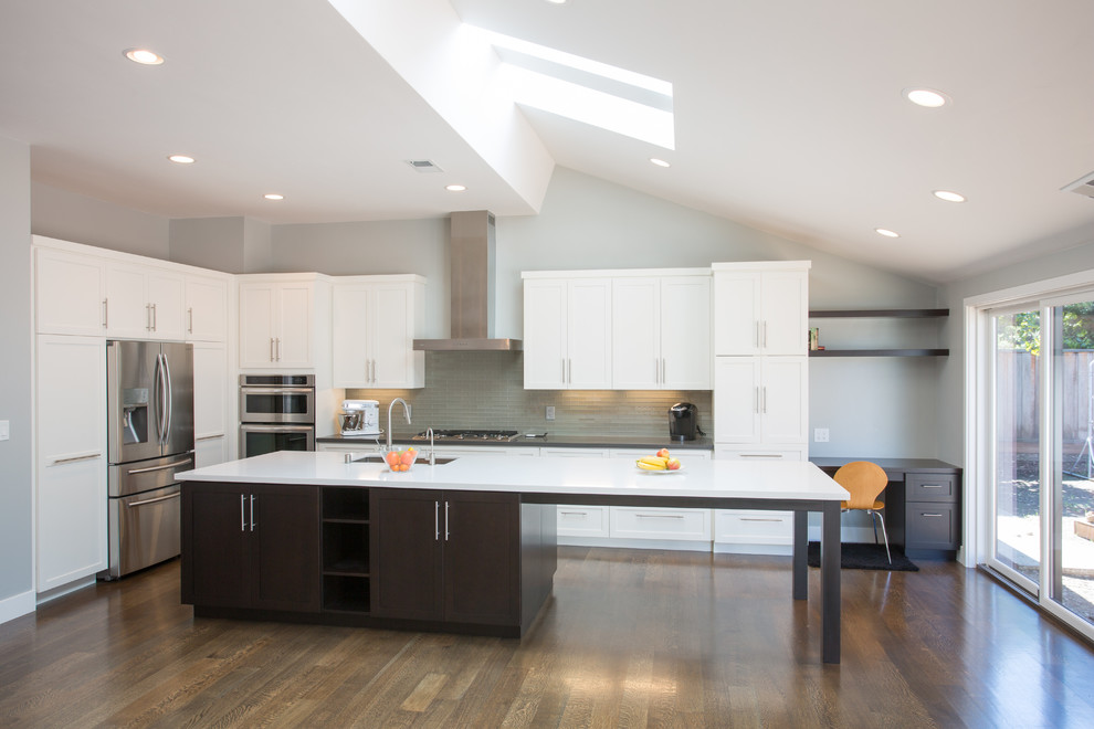 Large contemporary l-shaped open plan kitchen in San Francisco with a double-bowl sink, shaker cabinets, white cabinets, grey splashback, matchstick tile splashback, stainless steel appliances, medium hardwood floors, with island and quartzite benchtops.