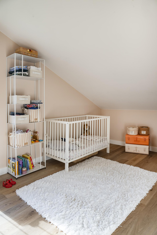 Cette image montre une chambre de bébé neutre design de taille moyenne avec un mur beige, parquet clair et un sol beige.