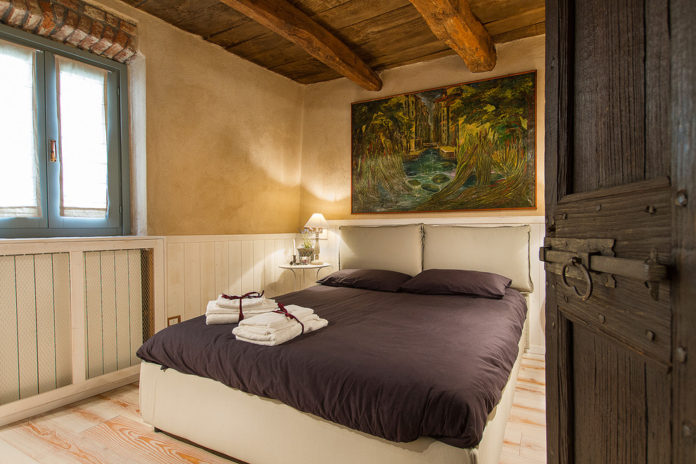 Design ideas for a country guest bedroom in Milan with beige walls and light hardwood floors.