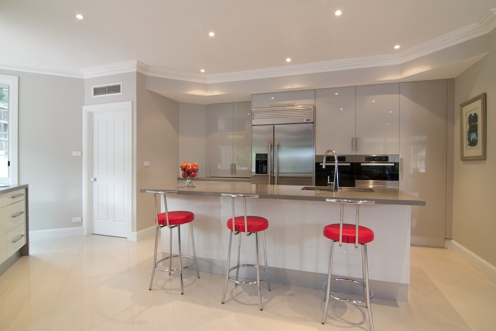 Inspiration for an expansive modern l-shaped eat-in kitchen in Sydney with an undermount sink, flat-panel cabinets, grey cabinets, quartz benchtops, grey splashback, glass sheet splashback, stainless steel appliances, ceramic floors and with island.