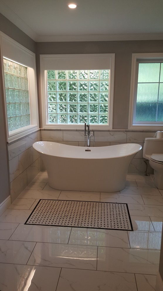 Example of a mid-sized transitional freestanding bathtub design with a two-piece toilet, beige walls and a hinged shower door