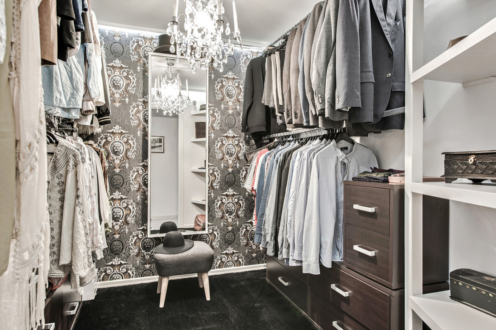 Design ideas for a mid-sized traditional gender-neutral walk-in wardrobe in Gothenburg with open cabinets, dark wood cabinets, carpet and black floor.