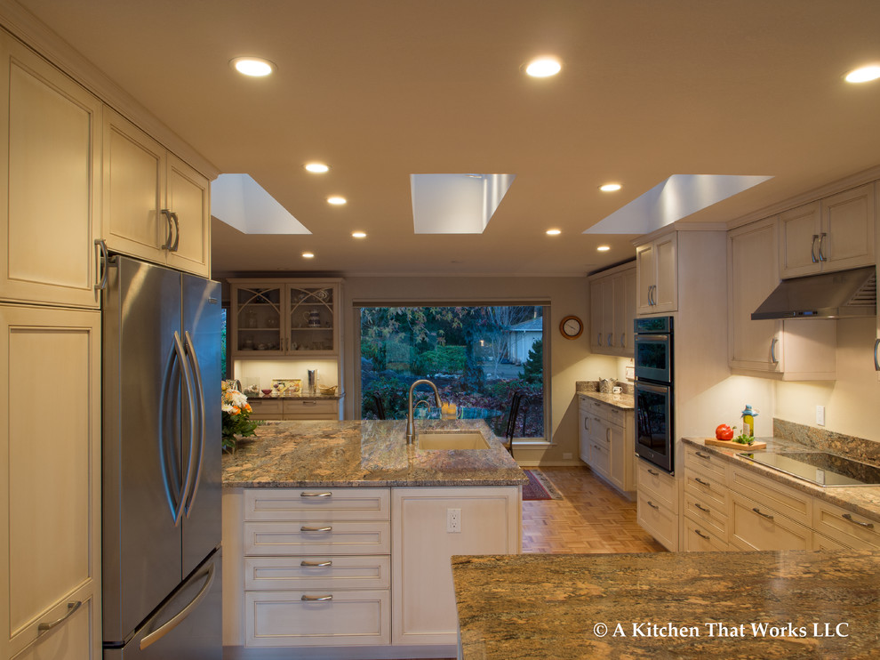 Inspiration for a large transitional u-shaped medium tone wood floor and brown floor eat-in kitchen remodel in Seattle with an undermount sink, recessed-panel cabinets, white cabinets, granite countertops, stone slab backsplash, stainless steel appliances, an island, brown backsplash and brown countertops