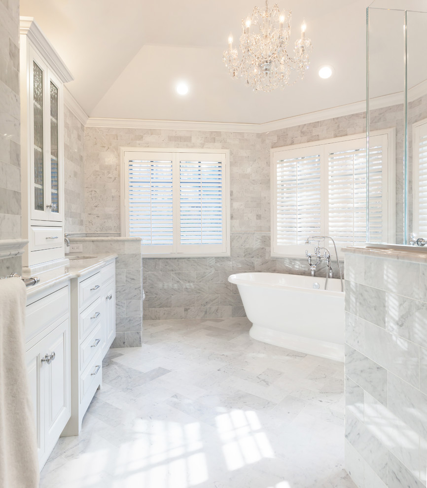 Inspiration for a large traditional master bathroom in New York with an undermount sink, white cabinets, marble benchtops, a freestanding tub, a corner shower, white tile, stone tile, grey walls, marble floors, raised-panel cabinets and a one-piece toilet.