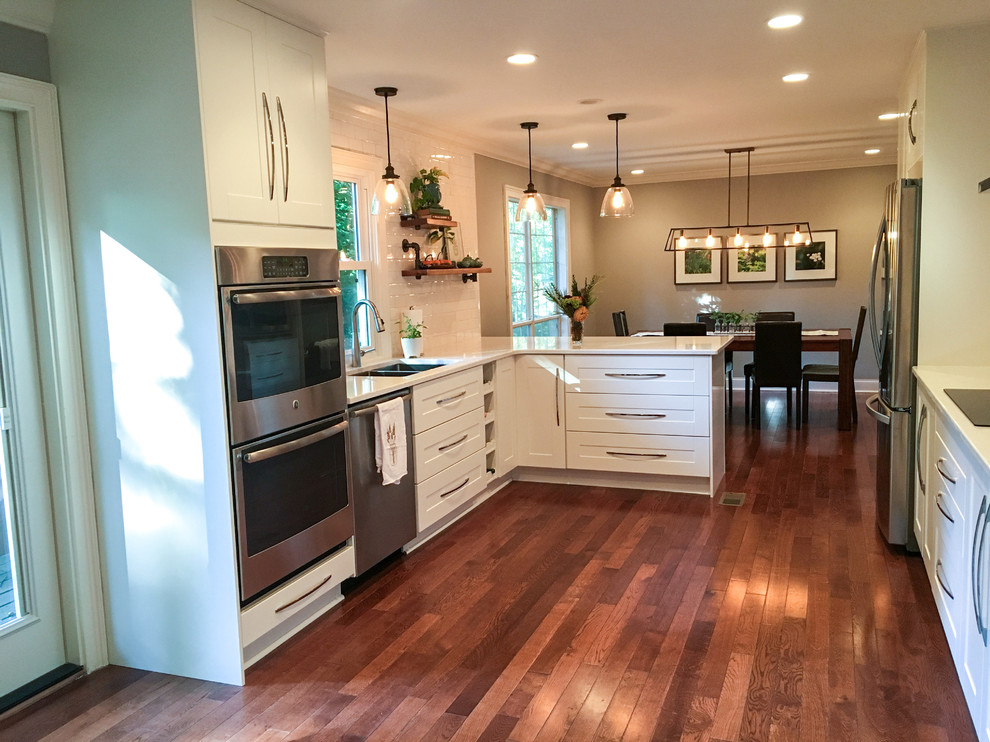 Mid-sized transitional galley dark wood floor eat-in kitchen photo with an undermount sink, recessed-panel cabinets, white cabinets, quartz countertops, white backsplash, subway tile backsplash, stainless steel appliances and a peninsula
