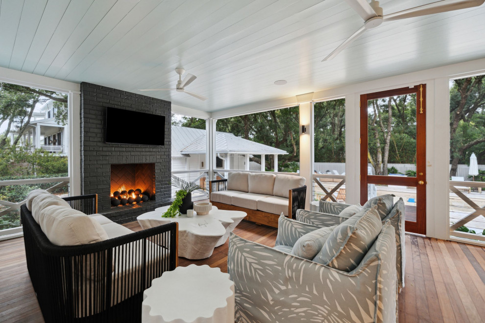 This is an example of a beach style backyard verandah in Charleston with with fireplace and cable railing.