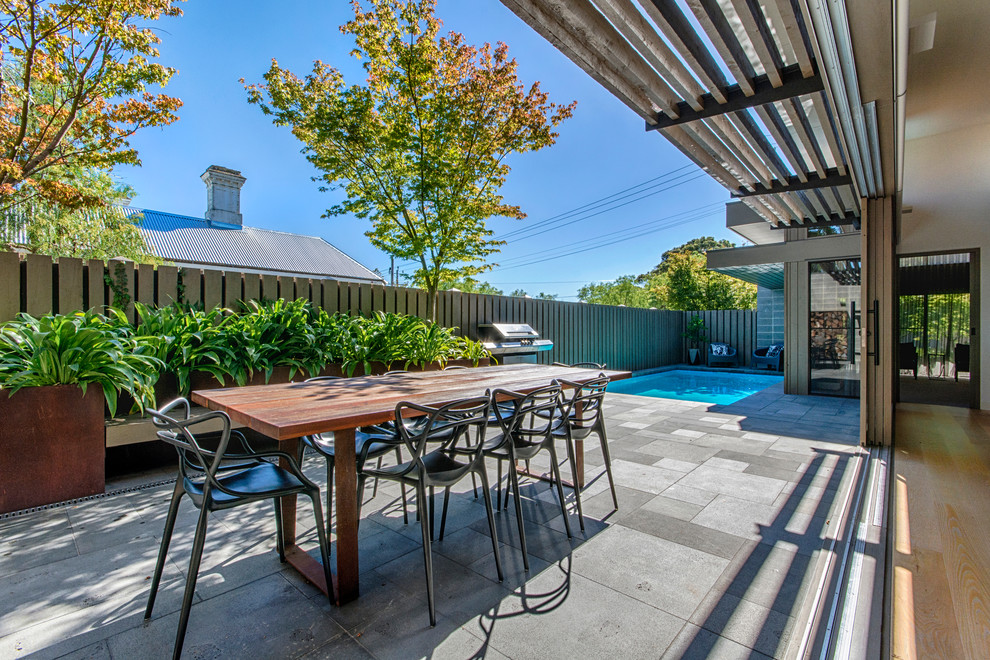 Contemporary backyard patio in Geelong with concrete pavers and an awning.