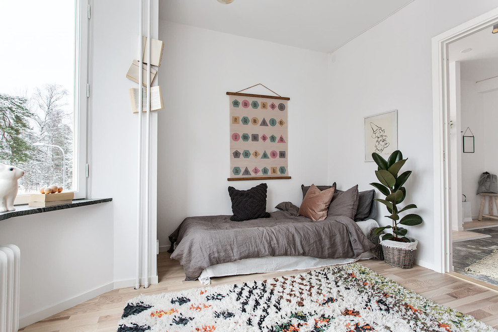 Design ideas for a mid-sized scandinavian gender-neutral kids' bedroom for kids 4-10 years old in Stockholm with white walls, beige floor and light hardwood floors.