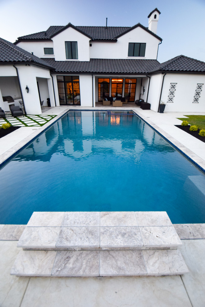 Large contemporary backyard rectangular lap pool in Dallas with a water feature.