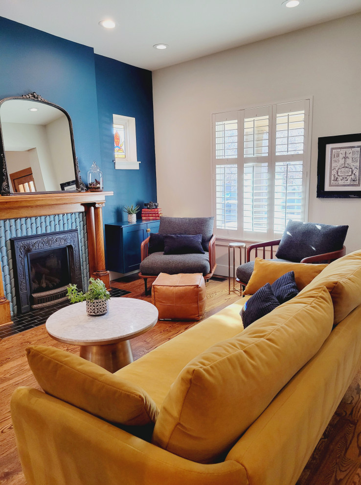 Стильный дизайн: гостиная комната среднего размера в стиле фьюжн с синими стенами, паркетным полом среднего тона, стандартным камином и фасадом камина из плитки - последний тренд