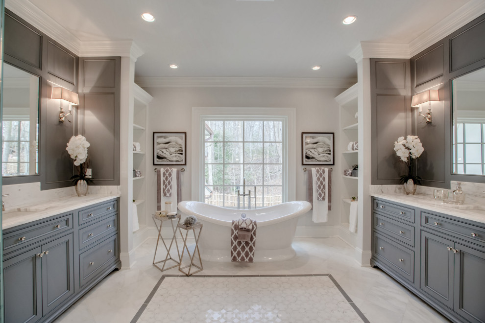 Expansive traditional master bathroom in Los Angeles with grey cabinets, a freestanding tub, a one-piece toilet, white walls, porcelain floors, an undermount sink, engineered quartz benchtops, white floor, white benchtops, an enclosed toilet and a double vanity.