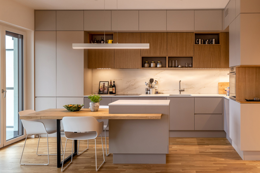 Contemporary l-shaped open plan kitchen in Berlin with flat-panel cabinets, beige cabinets, composite countertops, beige splashback, ceramic splashback, light hardwood flooring, an island and beige worktops.