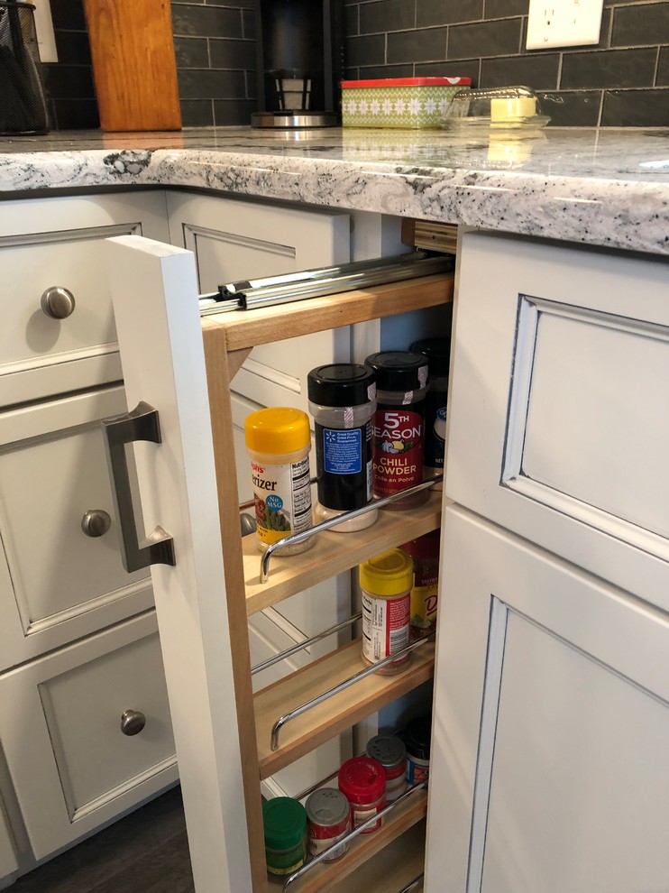 Small transitional l-shaped laminate floor and gray floor eat-in kitchen photo with an undermount sink, flat-panel cabinets, white cabinets, quartz countertops, gray backsplash, subway tile backsplash, white appliances and white countertops