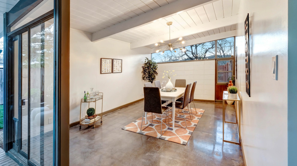 Foto di una sala da pranzo minimalista di medie dimensioni con pareti bianche, pavimento in cemento, pavimento grigio e travi a vista