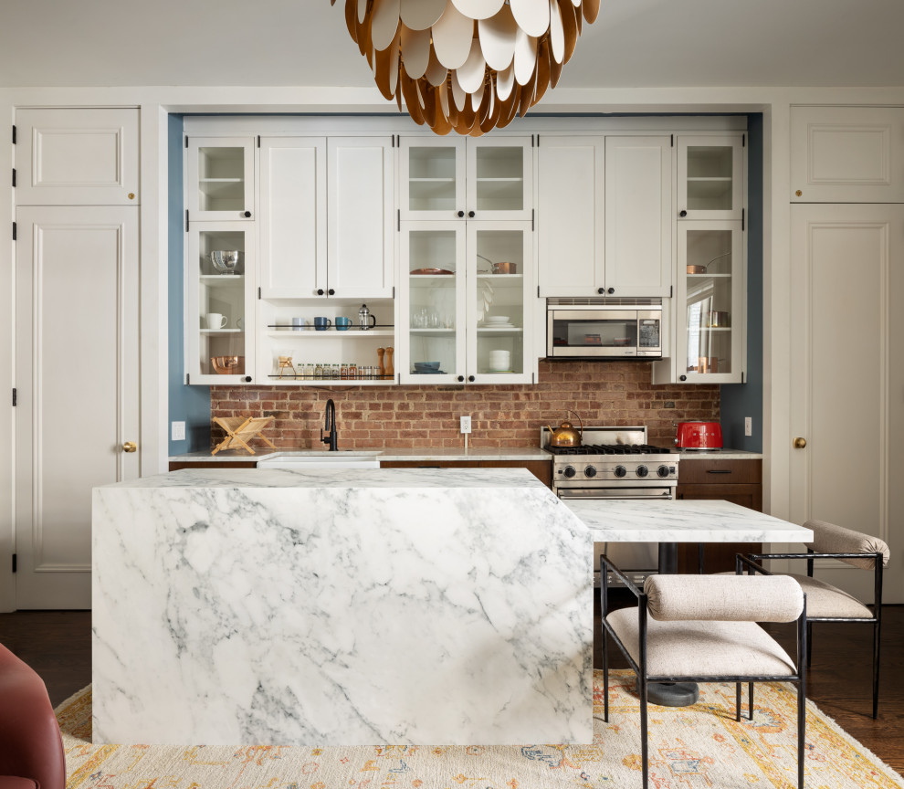 Inspiration for a small transitional dark wood floor and brown floor eat-in kitchen remodel in New York with a farmhouse sink, shaker cabinets, white cabinets, marble countertops, brick backsplash, stainless steel appliances, an island and white countertops