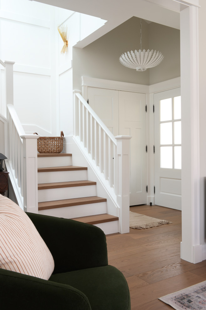 На фото: п-образная лестница среднего размера в классическом стиле с деревянными ступенями, крашенными деревянными подступенками, деревянными перилами и панелями на части стены с