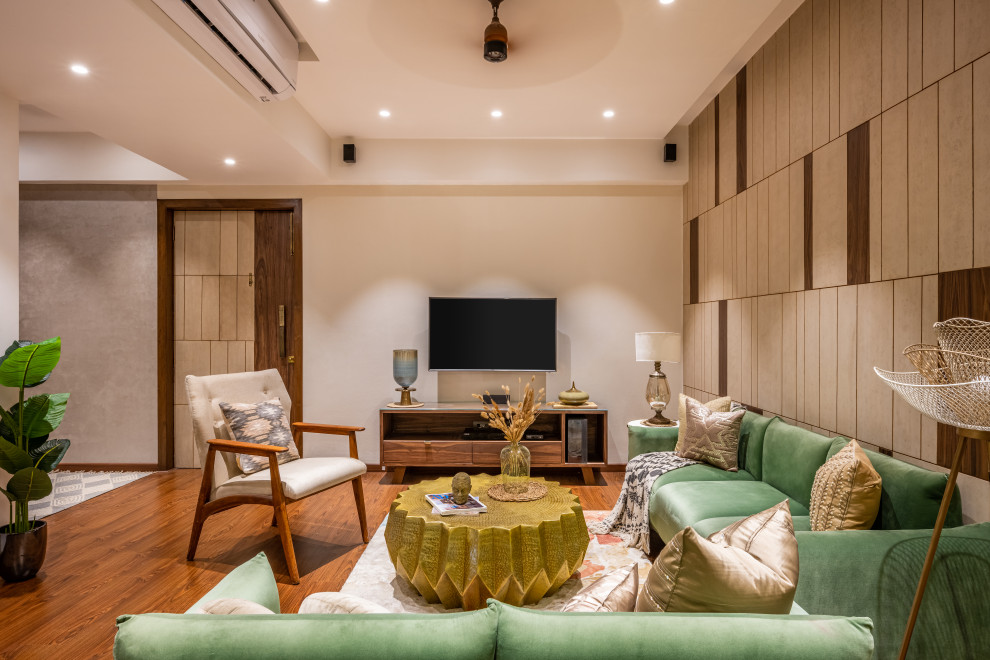 Modern living room in Mumbai with beige walls, light hardwood floors, a wall-mounted tv, brown floor and panelled walls.