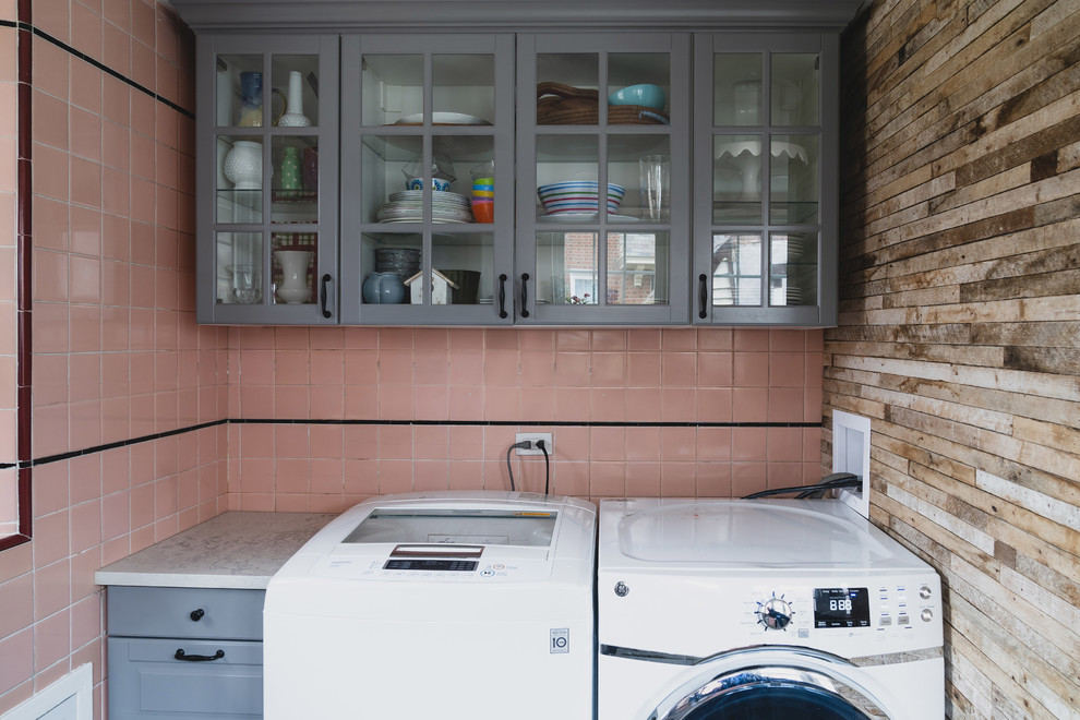 This is an example of a mid-sized modern u-shaped dedicated laundry room in Philadelphia with an utility sink, raised-panel cabinets, grey cabinets, quartz benchtops, pink walls, limestone floors, a side-by-side washer and dryer, beige floor and white benchtop.
