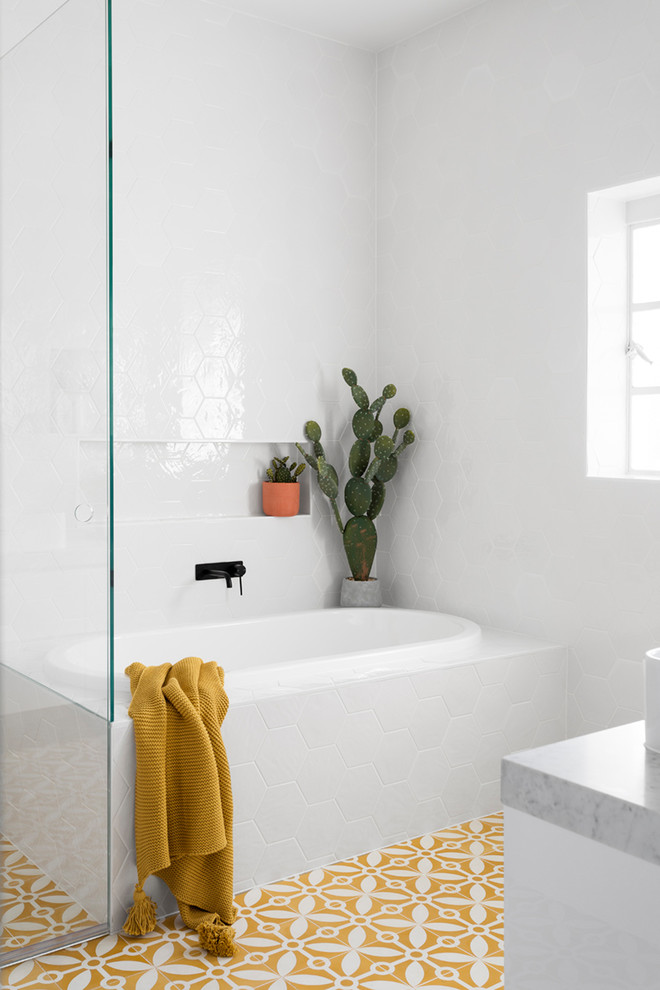 Photo of a large contemporary master bathroom in Melbourne with a drop-in tub, a corner shower, white tile, cement tiles, marble benchtops, yellow floor, a hinged shower door, flat-panel cabinets, white cabinets, a one-piece toilet, ceramic tile, white walls and a vessel sink.