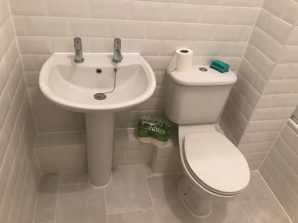 This is an example of a mid-sized traditional kids bathroom in London with a freestanding tub, a curbless shower, a one-piece toilet, white tile, ceramic tile, white walls, ceramic floors, a pedestal sink, white floor, a hinged shower door and a single vanity.