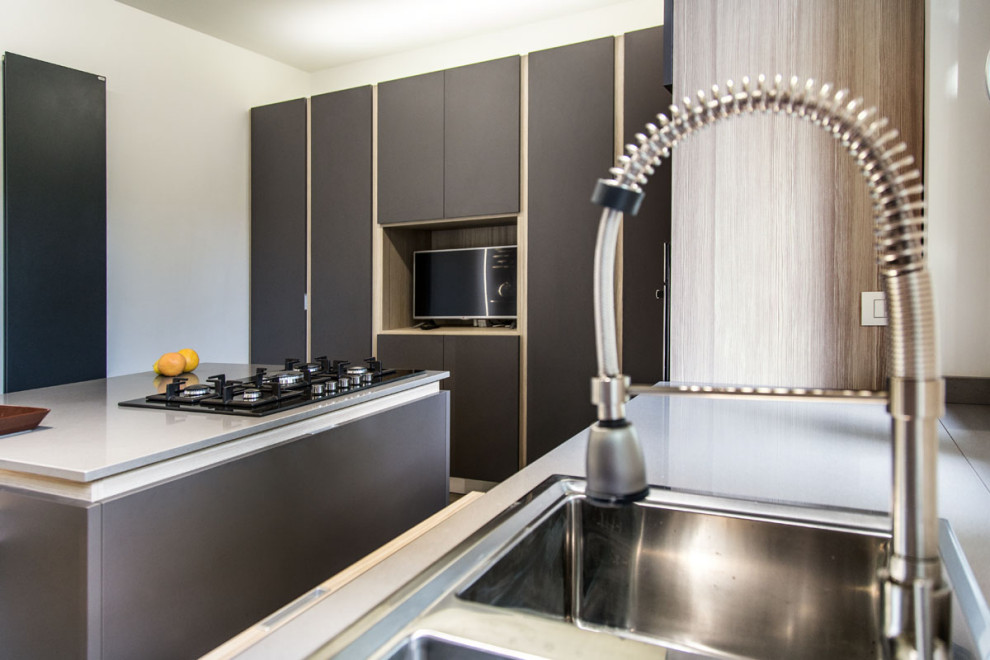 This is an example of a mid-sized modern l-shaped eat-in kitchen in Other with a double-bowl sink, flat-panel cabinets, light wood cabinets, solid surface benchtops, grey splashback, porcelain floors, with island, grey floor, grey benchtop and stainless steel appliances.