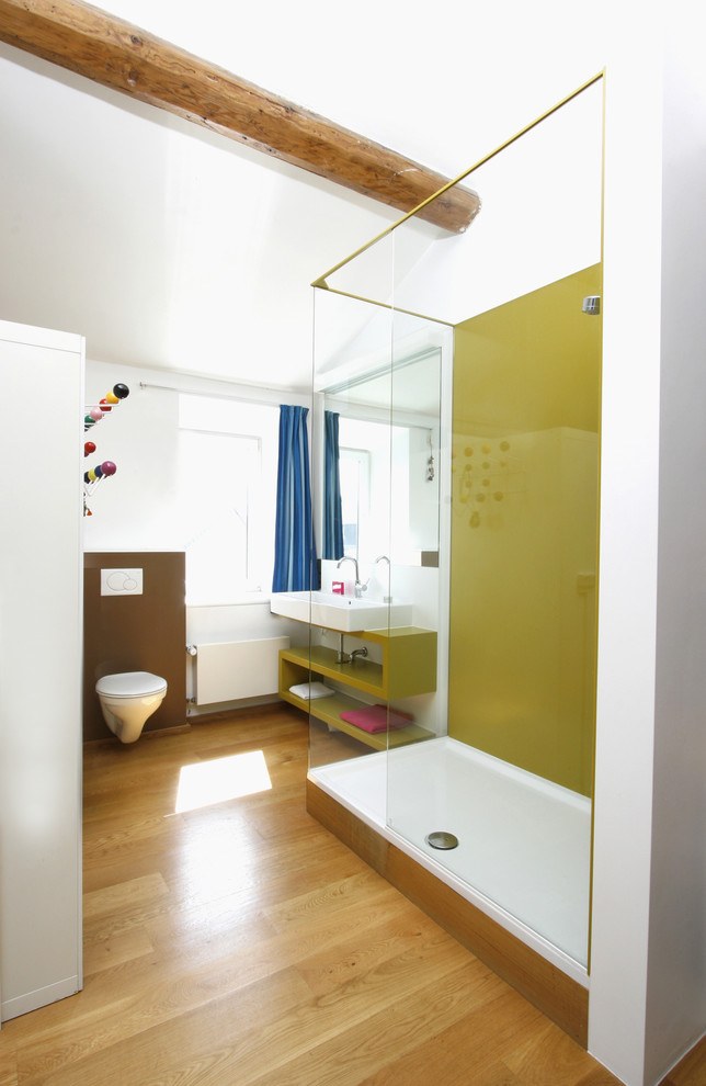 Inspiration for a mid-sized contemporary bathroom in Other with open cabinets, green cabinets, a wall-mount toilet, multi-coloured walls, medium hardwood floors, a vessel sink and an open shower.