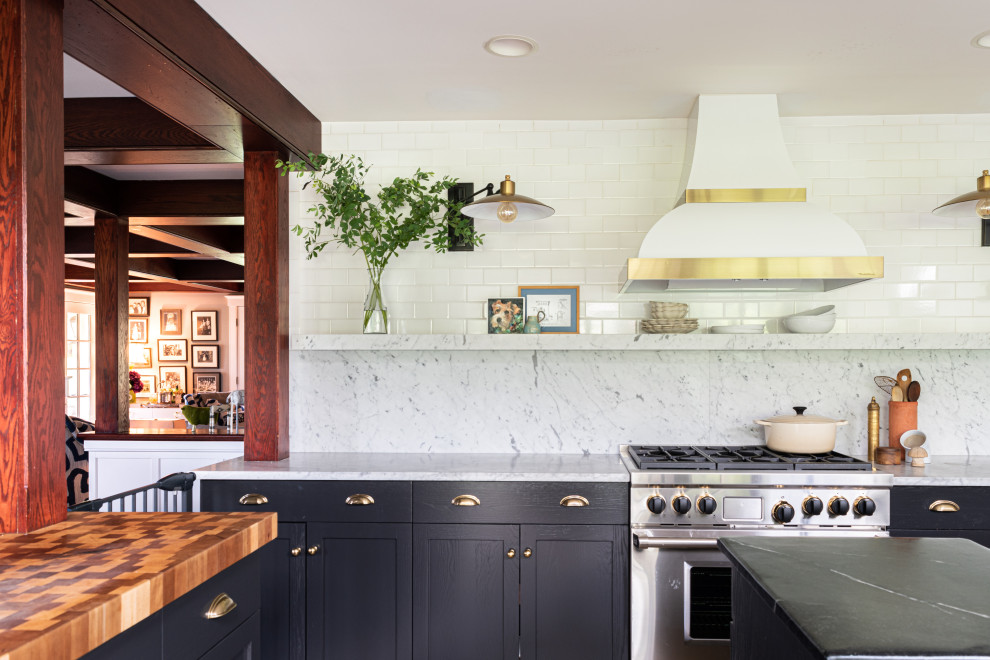 Photo of a mid-sized modern u-shaped eat-in kitchen in Philadelphia with a triple-bowl sink, flat-panel cabinets, black cabinets, marble benchtops, white splashback, marble splashback, stainless steel appliances, ceramic floors, with island, beige floor and white benchtop.