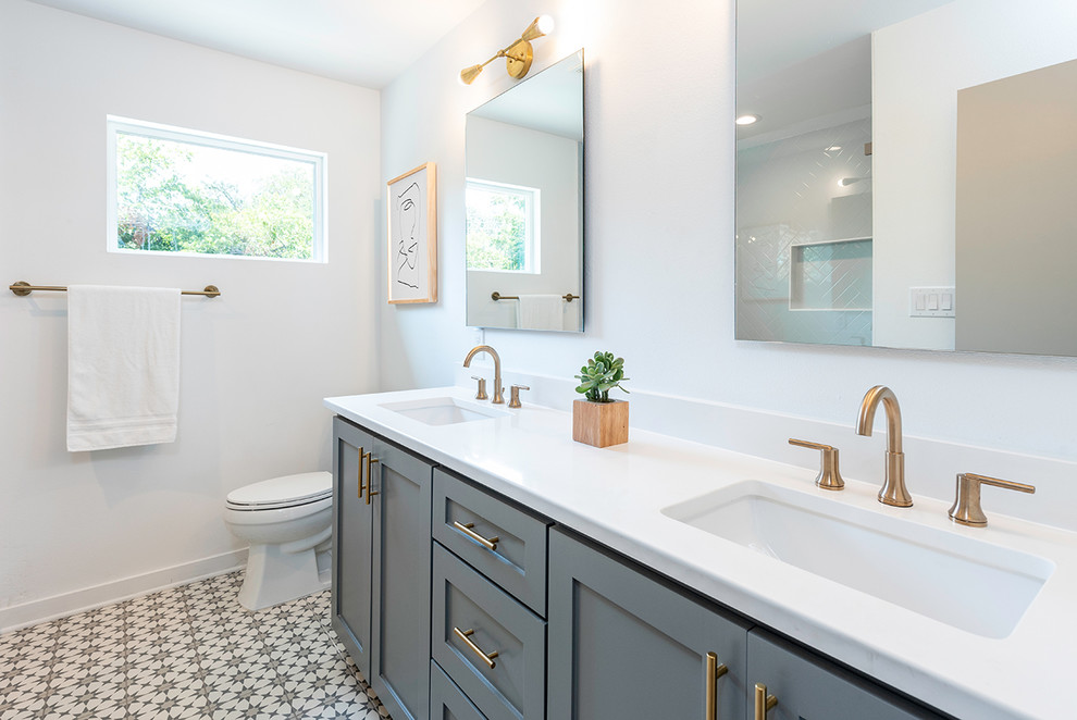 Mid-sized transitional 3/4 bathroom in Austin with shaker cabinets, grey cabinets, an alcove shower, a two-piece toilet, white walls, cement tiles, an undermount sink, multi-coloured floor, white benchtops and solid surface benchtops.