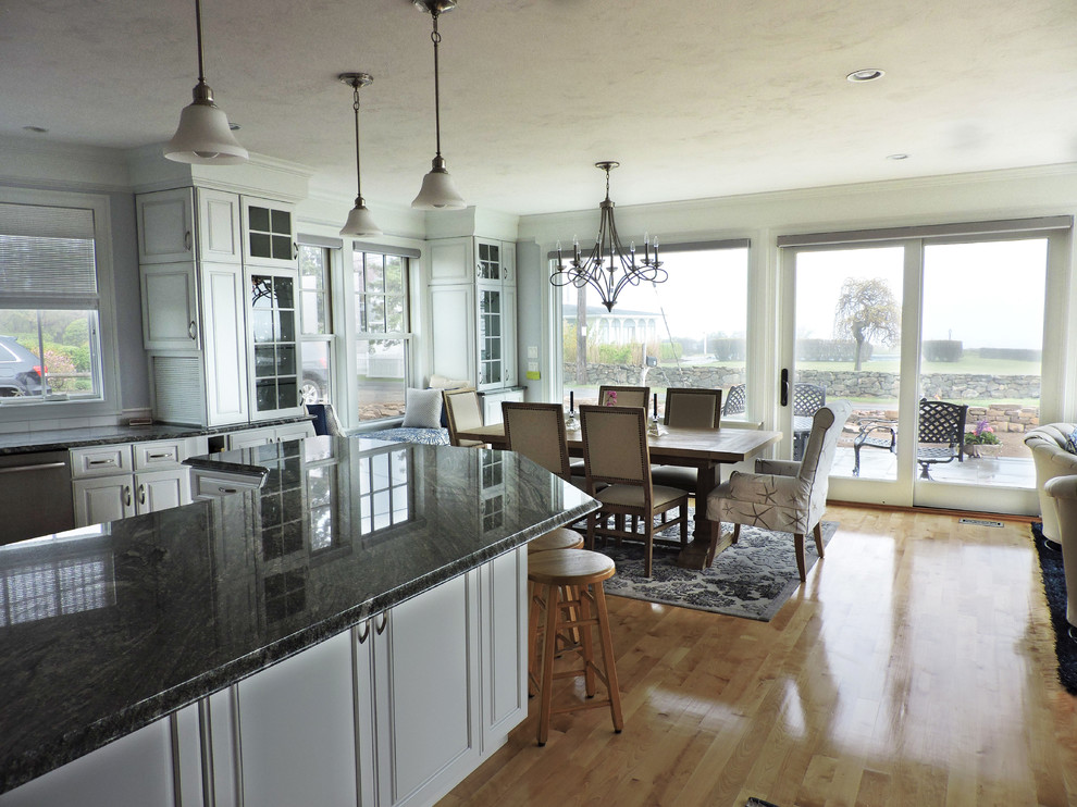 Large beach style u-shaped light wood floor and beige floor eat-in kitchen photo with white walls, raised-panel cabinets, white cabinets, granite countertops, white backsplash, subway tile backsplash, stainless steel appliances, an island, gray countertops and an undermount sink
