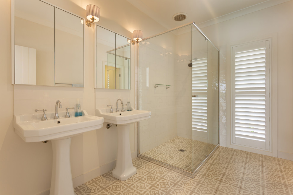 Design ideas for a mid-sized beach style master bathroom in Other with a corner shower, white tile, white walls, a pedestal sink, beige floor, a sliding shower screen and cement tiles.