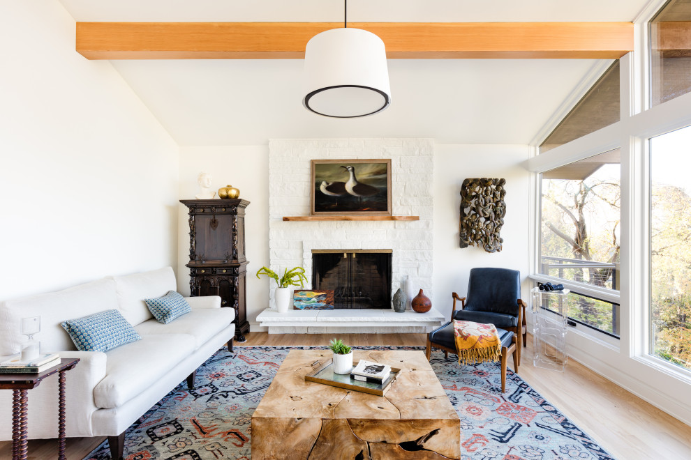 This is an example of an eclectic living room in Seattle with white walls and a stone fireplace surround.