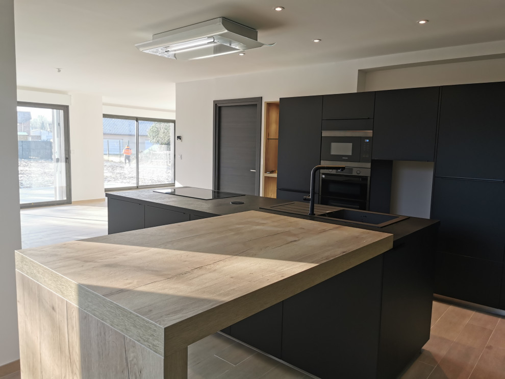 Inspiration for a large industrial l-shaped eat-in kitchen in Lille with a single-bowl sink, beaded inset cabinets, black cabinets, laminate benchtops, black appliances, ceramic floors, with island, brown floor and black benchtop.