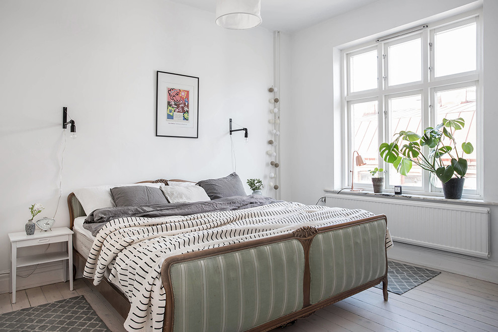 This is an example of a mid-sized traditional master bedroom in Gothenburg with white walls, light hardwood floors and no fireplace.