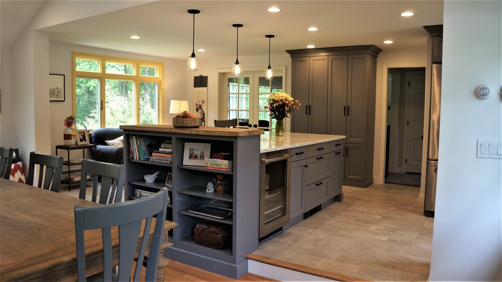 Mid-sized transitional galley porcelain tile and gray floor open concept kitchen photo in Boston with a farmhouse sink, recessed-panel cabinets, quartz countertops, white backsplash, porcelain backsplash, stainless steel appliances, an island and white countertops
