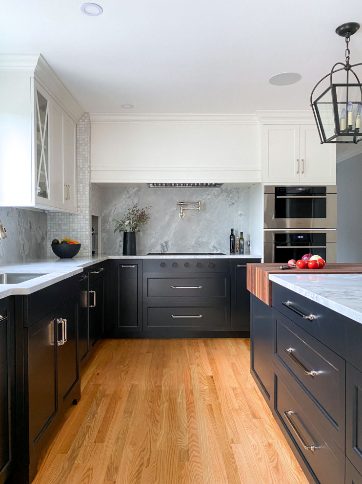 Example of a classic medium tone wood floor kitchen design in Boston with an undermount sink, shaker cabinets, black cabinets, quartzite countertops, gray backsplash, stainless steel appliances, an island and gray countertops
