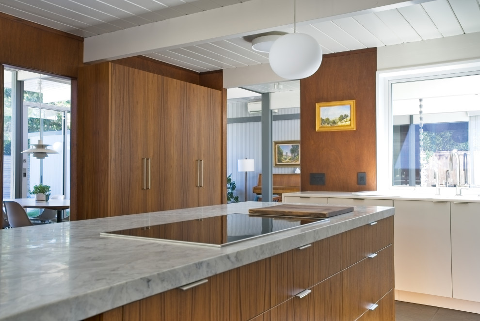 Design ideas for a large midcentury l-shaped open plan kitchen in Orange County with an undermount sink, flat-panel cabinets, white cabinets, quartzite benchtops, white splashback, ceramic splashback, white appliances, slate floors, with island, grey floor, multi-coloured benchtop and timber.