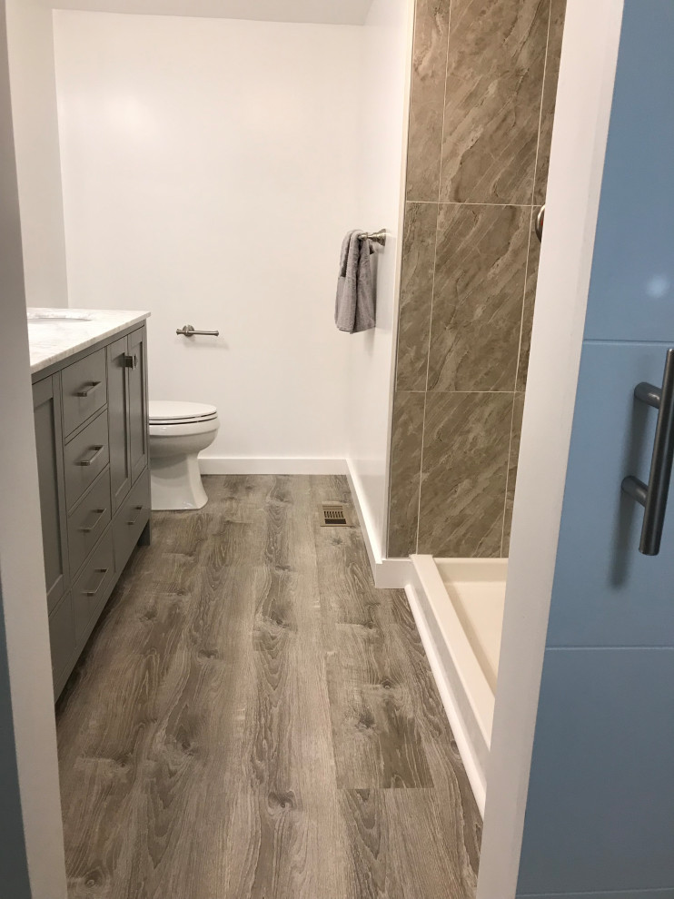 Photo of a mid-sized country master bathroom in Portland Maine with an alcove shower, vinyl floors, multi-coloured floor, an open shower, shaker cabinets, grey cabinets, a two-piece toilet, multi-coloured tile, porcelain tile, white walls, quartzite benchtops and white benchtops.