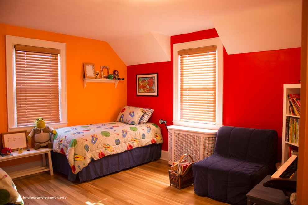 Traditional bedroom in New York with orange walls and medium hardwood floors.