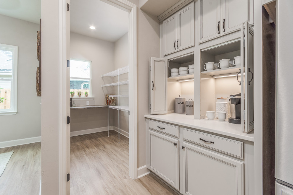 Bild på ett mellanstort vit vitt kök, med en enkel diskho, grå skåp, bänkskiva i kvartsit, beige stänkskydd, stänkskydd i stenkakel, rostfria vitvaror, vinylgolv, en köksö och brunt golv