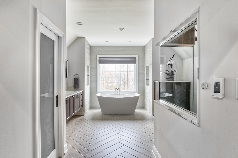 Design ideas for an expansive transitional master bathroom in New York with shaker cabinets, dark wood cabinets, engineered quartz benchtops, white benchtops, a freestanding tub, an alcove shower, gray tile, glass tile, beige walls, an undermount sink and a hinged shower door.